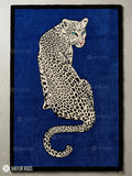 Rectangular hand-tufted leopard rug featuring a cream and black spotted leopard with turquoise eyes on a royal blue background and black border by Mayur Rugs.