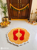 Diwali rangoli-inspired hand-tufted custom wool rug featuring red Lakshmi Charan-inspired footprints on a golden-yellow base with a scalloped ivory-white border by Mayur Rugs.
