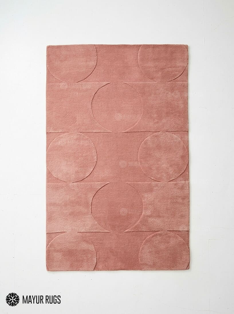 Rectangular blush rose pink area rug featuring a repeating circular geometric pattern and subtle horizontal lines on a light background by Mayur Rugs.
