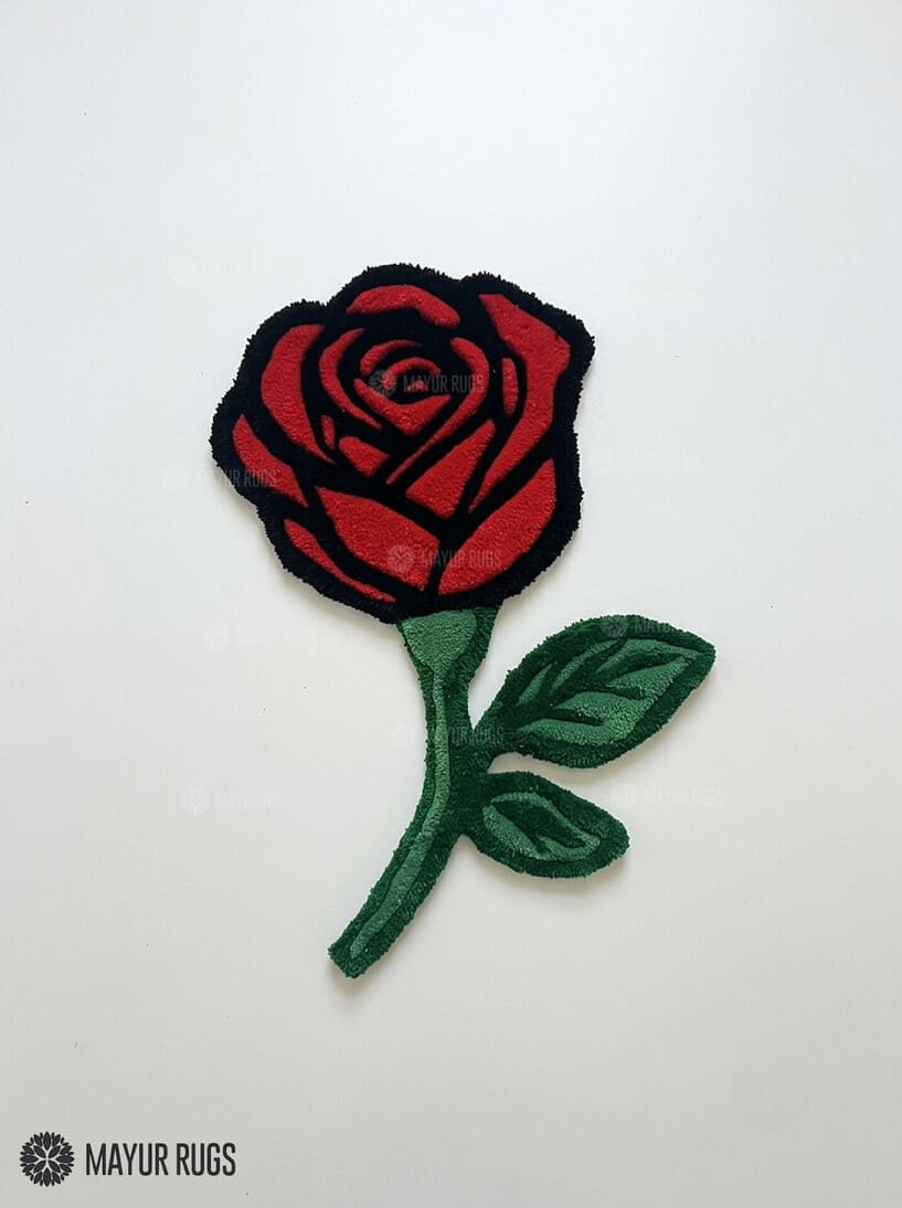 Red rose-shaped hand-tufted rug with crimson petals outlined in black, a deep green stem, and two green leaves by Mayur Rugs.