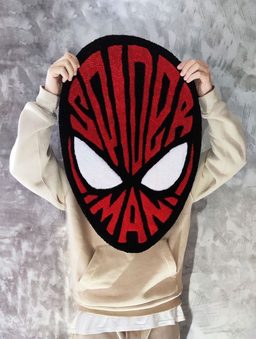 Spider-Man inspired hand-tufted custom wool rug featuring a red and black superhero mask design with large white eyes and graphic web detailing by Mayur Rugs.